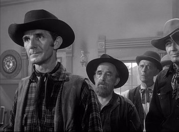 Movie still from “High Noon” (1952), directed by Fred Zinnemann – A group of men standing next to each other wearing hats; Medium shot, Low angle