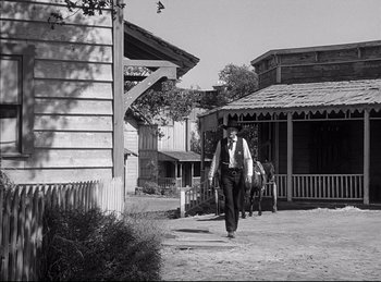 Movie still from “High Noon” (1952), directed by Fred Zinnemann – A man walking down the street in a black and white photo; Wide shot, Low angle
