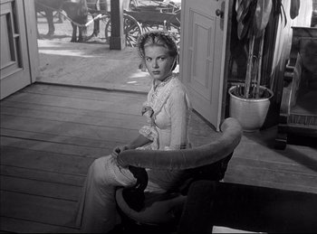 Movie still from “High Noon” (1952), directed by Fred Zinnemann – A black and white photo of a woman sitting in a chair; Medium shot, Low angle