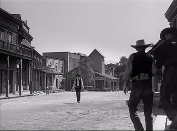 Movie still from “High Noon” (1952), directed by Fred Zinnemann – A man walking down a street in a western town; Wide shot, Low angle