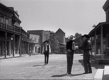 Movie still from “High Noon” (1952), directed by Fred Zinnemann – A group of men standing on a dirt road; Wide shot, Over the shoulder angle