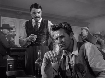 Movie still from “High Noon” (1952), directed by Fred Zinnemann – A man sitting in front of another man in front of another man; Medium shot, Over the shoulder angle