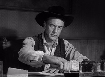 Movie still from “High Noon” (1952), directed by Fred Zinnemann – An old photo of a man wearing a cowboy hat; Medium shot, Low angle