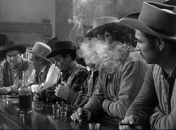 Movie still from “High Noon” (1952), directed by Fred Zinnemann – A black and white photo of a group of men sitting at a table; Medium shot, Low angle