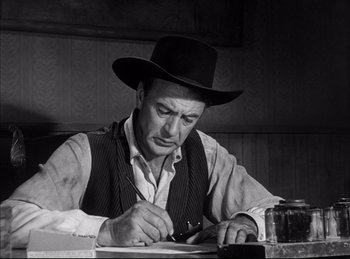 Movie still from “High Noon” (1952), directed by Fred Zinnemann – A man in a hat is writing on a paper; Close Up shot, Low angle