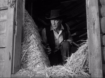 Movie still from “High Noon” (1952), directed by Fred Zinnemann – A man in a cowboy hat is in a hay barn; Medium shot, Low angle