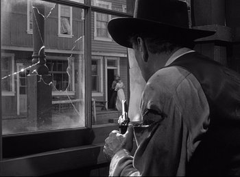 Movie still from “High Noon” (1952), directed by Fred Zinnemann – A black and white photo of a man looking out of a window; Medium shot, Low angle