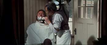 Movie still from “High Plains Drifter” (1973), directed by Clint Eastwood – A man getting a haircut from a barber; Medium shot, Over the shoulder angle