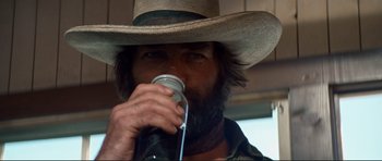 Movie still from “High Plains Drifter” (1973), directed by Clint Eastwood – A man in a cowboy hat drinking from a cup; Close Up shot, Low angle