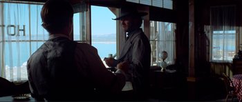 Movie still from “High Plains Drifter” (1973), directed by Clint Eastwood – A man wearing a cowboy hat is standing in front of a window; Medium shot, Over the shoulder angle