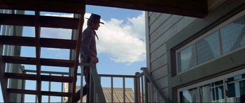 Movie still from “High Plains Drifter” (1973), directed by Clint Eastwood – A man wearing a cowboy hat walking down the stairs of a house; Wide shot, Low angle