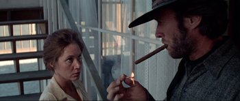 Movie still from “High Plains Drifter” (1973), directed by Clint Eastwood – A man lighting a cigarette in front of a woman; Medium shot, Low angle