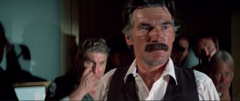 Movie still from “High Plains Drifter” (1973), directed by Clint Eastwood – A man with a beard and mustache and another man with a beard and mustache; Close Up shot, Over the shoulder angle