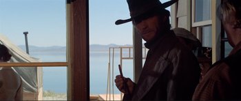 Movie still from “High Plains Drifter” (1973), directed by Clint Eastwood – A man wearing a hat and holding a knife; Medium shot, Low angle
