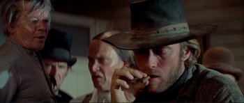 Movie still from “High Plains Drifter” (1973), directed by Clint Eastwood – A man in a cowboy hat talking on a cell phone; Close Up shot, Low angle