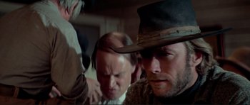 Movie still from “High Plains Drifter” (1973), directed by Clint Eastwood – A group of men standing next to each other in a room; Close Up shot, Low angle