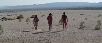 Movie still from “High Plains Drifter” (1973), directed by Clint Eastwood – A group of men walking across a barren field; Extreme Wide shot, Low angle