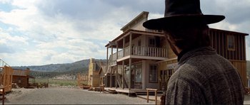 Movie still from “High Plains Drifter” (1973), directed by Clint Eastwood – A man standing in front of an old western style building; Wide shot, Low angle