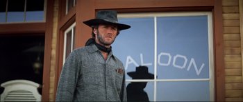 Movie still from “High Plains Drifter” (1973), directed by Clint Eastwood – A man wearing a hat standing in front of a building; Medium shot, Low angle