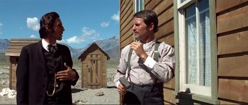 Movie still from “High Plains Drifter” (1973), directed by Clint Eastwood – A man standing in front of an outhouse; Medium shot, Low angle