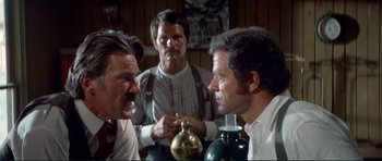 Movie still from “High Plains Drifter” (1973), directed by Clint Eastwood – A group of men sitting around a table; Medium shot, Over the shoulder angle