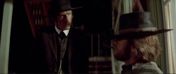 Movie still from “High Plains Drifter” (1973), directed by Clint Eastwood – A man wearing a hat and a suit; Close Up shot, Over the shoulder angle