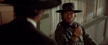 Movie still from “High Plains Drifter” (1973), directed by Clint Eastwood – A man wearing a hat and a jacket; Medium shot, Over the shoulder angle