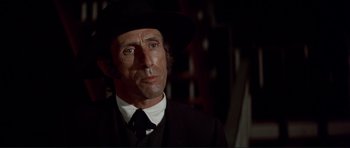 Movie still from “High Plains Drifter” (1973), directed by Clint Eastwood – A person wearing a suit and a hat; Close Up shot, Low angle