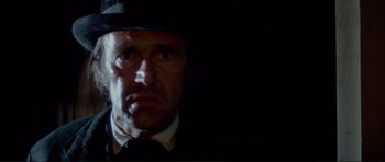 Movie still from “High Plains Drifter” (1973), directed by Clint Eastwood – A person wearing a suit and hat; Close Up shot, Low angle