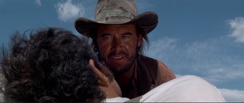 Movie still from “High Plains Drifter” (1973), directed by Clint Eastwood – A man in a cowboy hat is looking at another man; Close Up shot, Over the shoulder angle