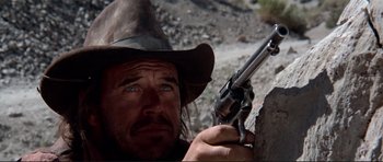 Movie still from “High Plains Drifter” (1973), directed by Clint Eastwood – A man in a cowboy hat holding a gun in his hand; Close Up shot, Low angle