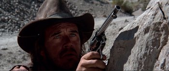 Movie still from “High Plains Drifter” (1973), directed by Clint Eastwood – A man in a cowboy hat holding a gun in his hand; Close Up shot, Low angle