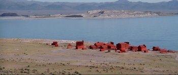Movie still from “High Plains Drifter” (1973), directed by Clint Eastwood – A group of red buildings sitting next to a body of water; Extreme Wide shot, High angle