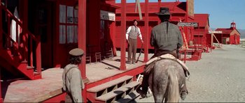 Movie still from “High Plains Drifter” (1973), directed by Clint Eastwood – Two men on horses on a stage in a western town; Wide shot, Over the shoulder angle