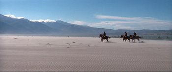Movie still from “High Plains Drifter” (1973), directed by Clint Eastwood – A man riding a horse across a sandy beach; Extreme Wide shot, High angle