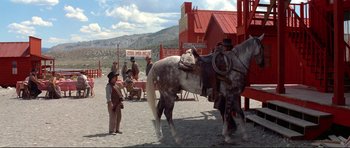 Movie still from “High Plains Drifter” (1973), directed by Clint Eastwood – A group of men standing around a horse; Wide shot, Low angle