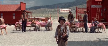 Movie still from “High Plains Drifter” (1973), directed by Clint Eastwood – A man in a hat and vest holding a rifle; Wide shot, Over the shoulder angle