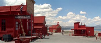 Movie still from “High Plains Drifter” (1973), directed by Clint Eastwood – A man riding a horse down a street near buildings; Extreme Wide shot, Low angle