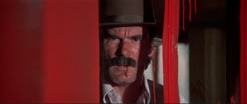 Movie still from “High Plains Drifter” (1973), directed by Clint Eastwood – A man with a mustache wearing a top hat; Close Up shot, Low angle