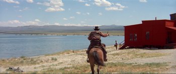 Movie still from “High Plains Drifter” (1973), directed by Clint Eastwood – A man riding a horse near a body of water; Extreme Wide shot, Low angle