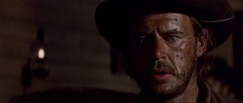 Movie still from “High Plains Drifter” (1973), directed by Clint Eastwood – A person wearing a hat and looking sad; Close Up shot, Low angle