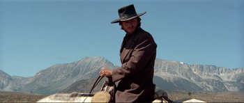 Movie still from “High Plains Drifter” (1973), directed by Clint Eastwood – A man riding a horse with a mountain in the background; Medium shot, Low angle
