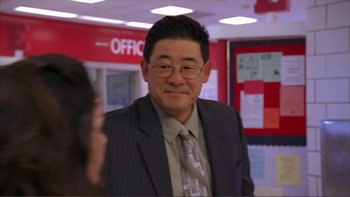 Movie still from “High School Musical” (2006), directed by Kenny Ortega – A man in a suit and tie in an office setting; Close Up shot, Over the shoulder angle