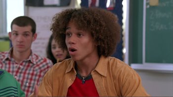 Movie still from “High School Musical” (2006), directed by Kenny Ortega – A young man with curly brown hair is looking surprised; Close Up shot, Over the shoulder angle