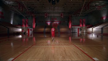 Movie still from “High School Musical” (2006), directed by Kenny Ortega – A person holding an umbrella while standing in a gym; Extreme Wide shot, High angle