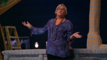 Movie still from “High School Musical” (2006), directed by Kenny Ortega – An older woman in a purple shirt and a necklace; Medium shot, Low angle