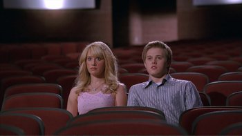 Movie still from “High School Musical” (2006), directed by Kenny Ortega – A man and a woman are sitting in a movie theater; Medium shot, Low angle