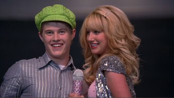 Movie still from “High School Musical” (2006), directed by Kenny Ortega – A man and a woman posing for a picture with a microphone; Close Up shot, Low angle