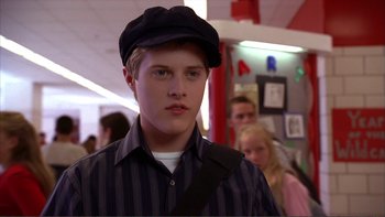 Movie still from “High School Musical” (2006), directed by Kenny Ortega – A young man wearing a black hat and a striped shirt; Close Up shot, High angle