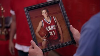 Movie still from “High School Musical” (2006), directed by Kenny Ortega – A person holding a picture of a man in a basketball uniform; Close Up shot, Over the shoulder angle